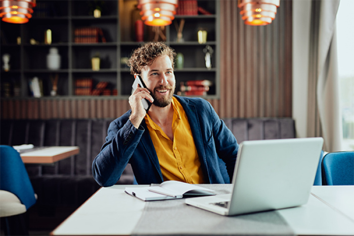 Man on cell phone working with laptop